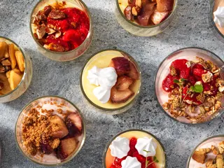 Många olika färgglada små desserter i glas