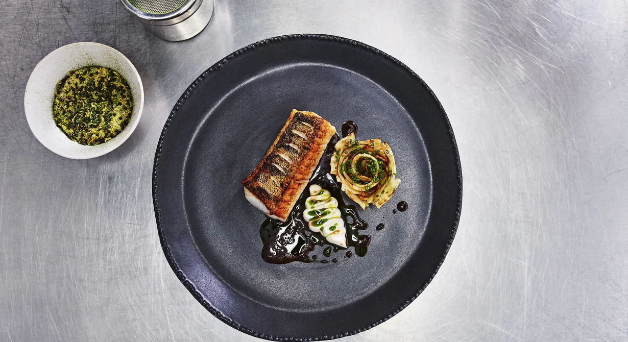 Den stekta gösen serveras med sotad rotselleri, puffad quinoa med citron och dill, rökt crème fraiche samt timjanolja. En varm kycklingsky med rödvin serveras till. Ringla gärna den varma såsen på tallriken framför gästen. Såsen ger rätten extra värme vid serveringen.